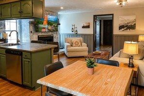 A kitchen with a dishwasher, a dining area with a table and chairs, a sofa, and a lamp. - Breathtaking Views at Dollys Castle unit 7 (Sevierville)