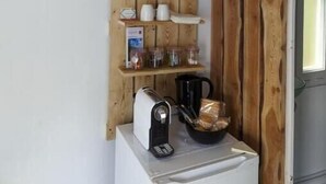 A compact kitchen with a wooden wall-mounted shelf holding glassware, a toaster, and a kettle. - Cabane Pour Amoureux (Daluis)