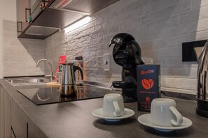 Eine moderne Küche mit einer Kaffeemaschine, zwei Tassen auf einer Arbeitsplatte und einer Packung Morettino Kaffeekapseln.