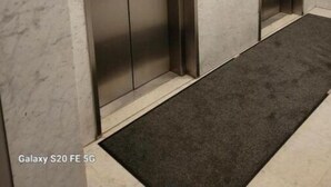 Un pasillo con dos ascensores y suelo de mármol.
