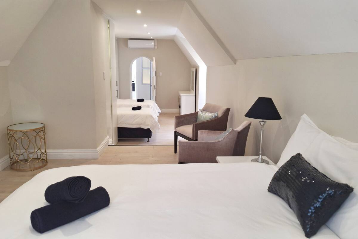 A bedroom with a large bed, a chair, a lamp, and a small table.