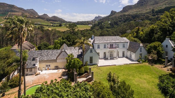 A large estate with multiple buildings, a well-maintained lawn, and a view of the surrounding hills. - Akamah Estate (Cape Town)