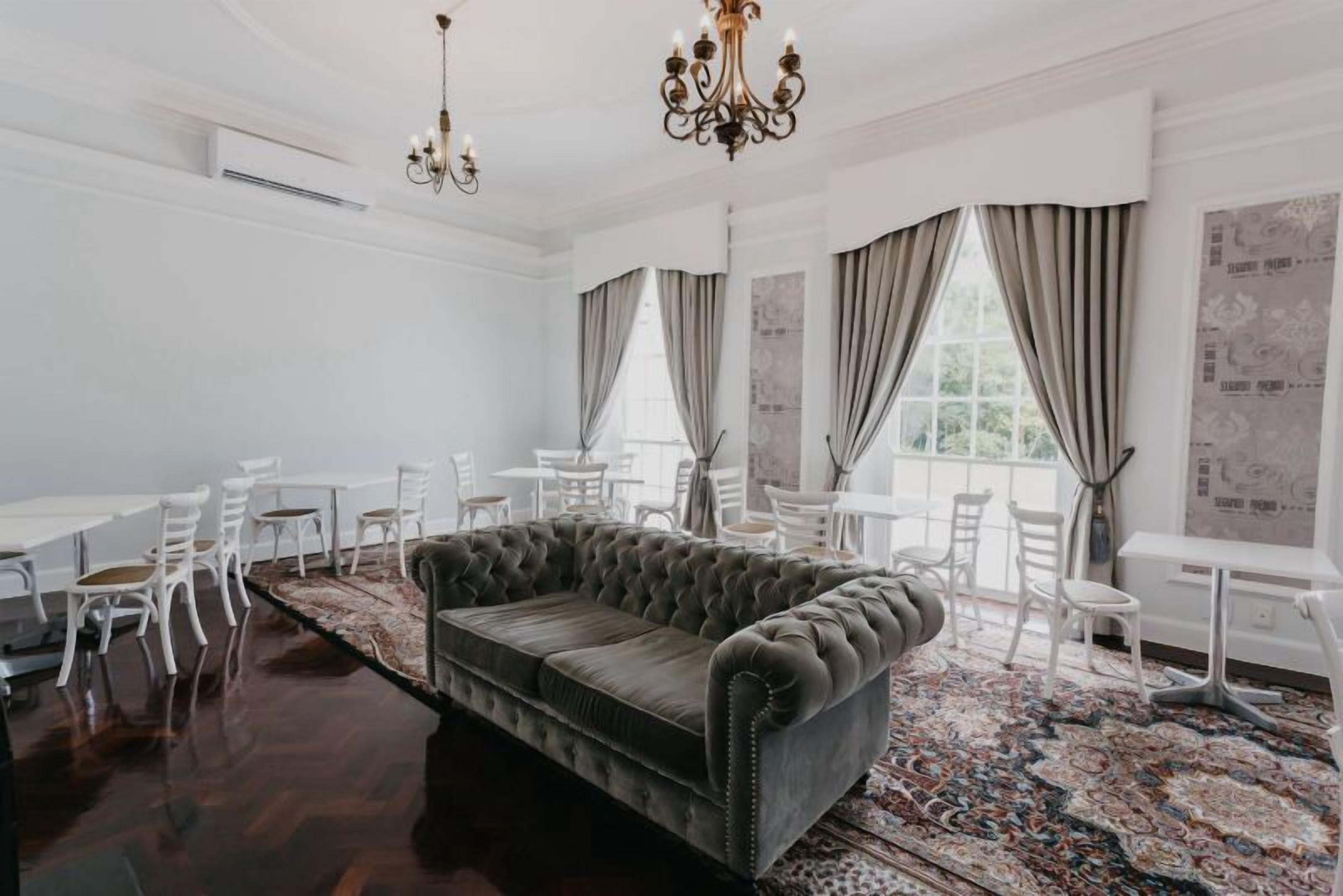 Ein geräumiger Raum mit einem großen, gepolsterten Sofa, weißen Stühlen und einem gemusterten Teppich.