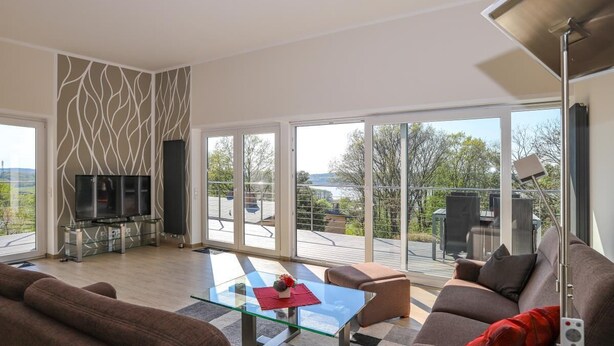 A modern living room with a glass coffee table, a sofa, and a TV on a stand. - Amselresidenz 5 - ADLERHORST (Binz)