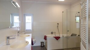 A modern bathroom with two sinks, a bathtub, a glass shower enclosure, and a toilet. - Amselresidenz 5 - ADLERHORST (Binz)