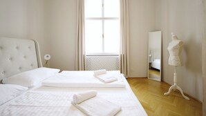 A hotel room with a large bed, a dresser, a mirror, and a mannequin. - HeyMi Apartments Karlsplatz (Vienna)