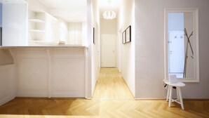 A hallway with a wooden floor, white walls, and a white door at the end. - HeyMi Apartments Karlsplatz (Vienna)