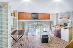 A compact kitchen with a dining area, a TV, and a microwave.