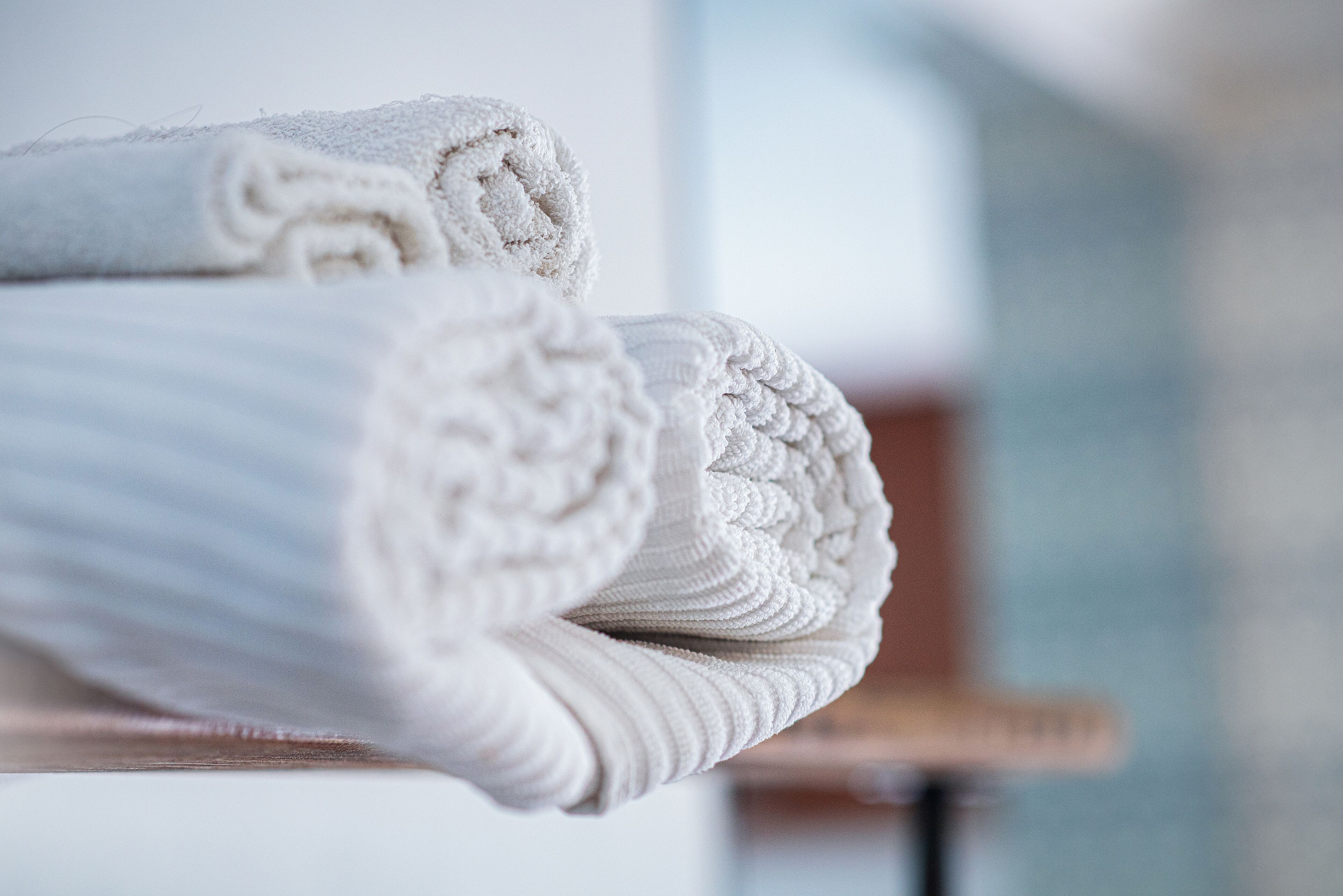 Een stapel netjes gevouwen witte handdoeken op een houten ondergrond.