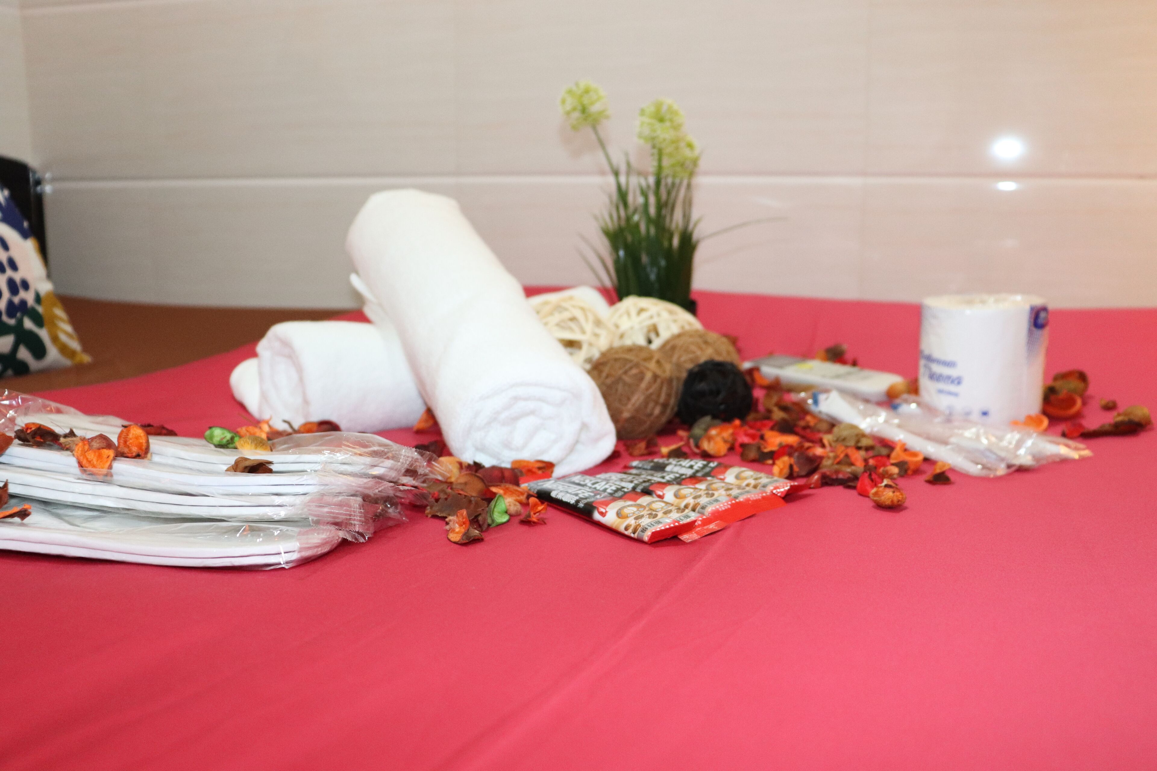A table with various items including rolled towels, a plant, and packaged snacks.