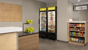 A kitchenette with two refrigerators labeled "cold" and "really cold," a shelf with apples, and a pantry stocked with snacks.