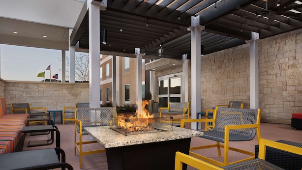 An outdoor seating area with a fire feature, stone walls, and modern furniture.