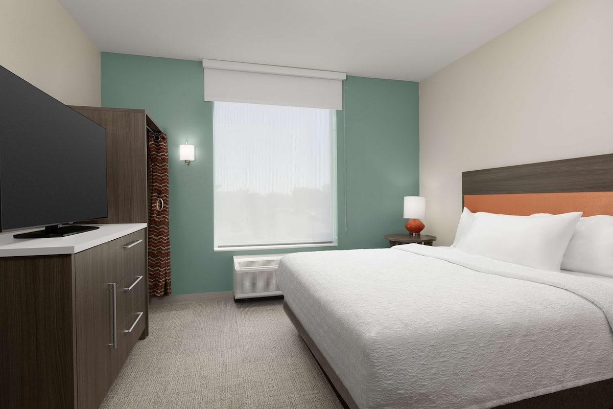Een hotelkamer met een bed, een televisie, een verwarming en een raam met uitzicht.