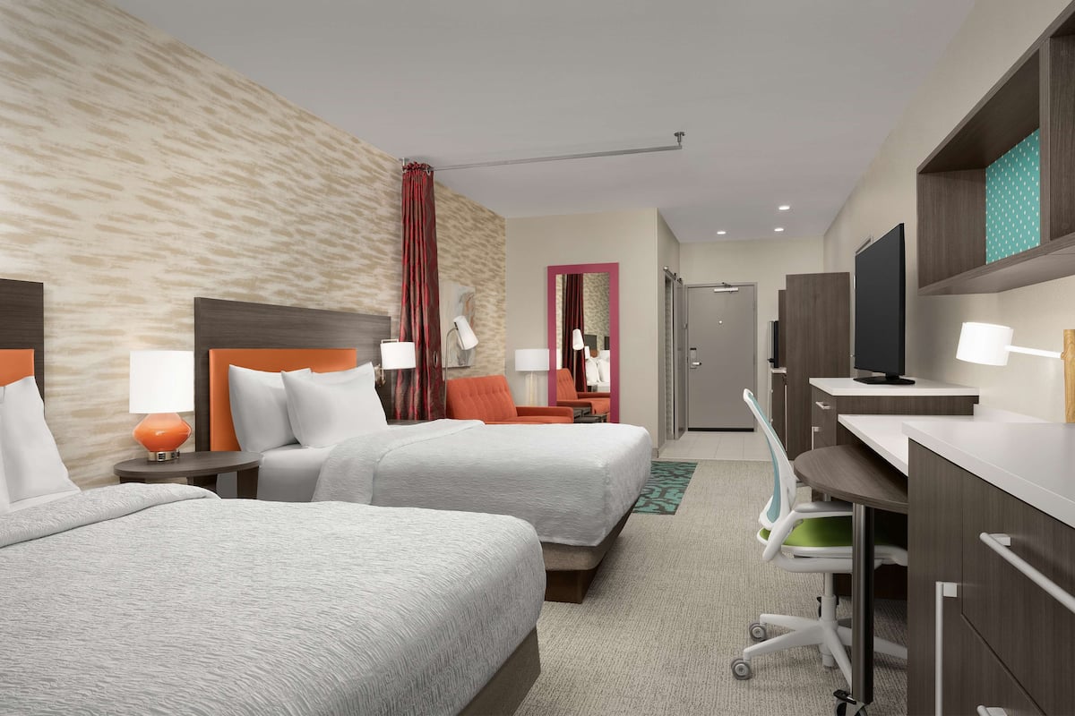 Een hotelkamer met twee bedden, een bureau, een televisie en een badkamer.