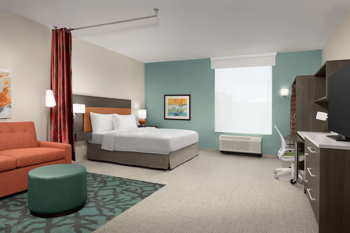 Een hotelkamer met een bed, een bureau, een stoel, een bank en een klein pouf.