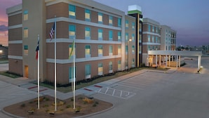 A multi-story hotel with a modern design, featuring a covered entrance and a parking lot.