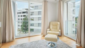 Moderni olohuone, jossa on suuri liukuovi, beige nojatuoli ja valkoinen matto.
