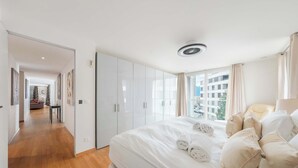 Hotellihuone, jossa on suuri sänky, kattotuuletin ja näkymä ulkopuolella oleviin rakennuksiin.