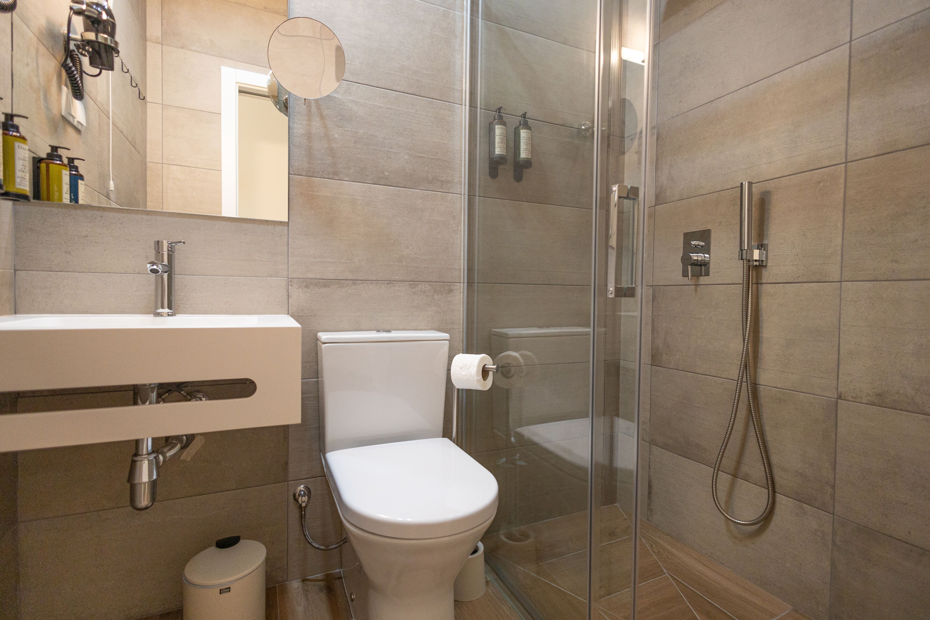 A modern bathroom with a toilet, sink, and glass shower enclosure.