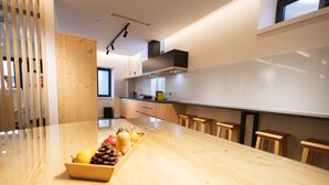 A modern kitchen with a wooden countertop, a fruit bowl, and bar stools. - Watts House (Seia)