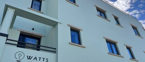 Un edificio moderno con un letrero que dice 'Watts Entradas', indicando la entrada de un hotel.