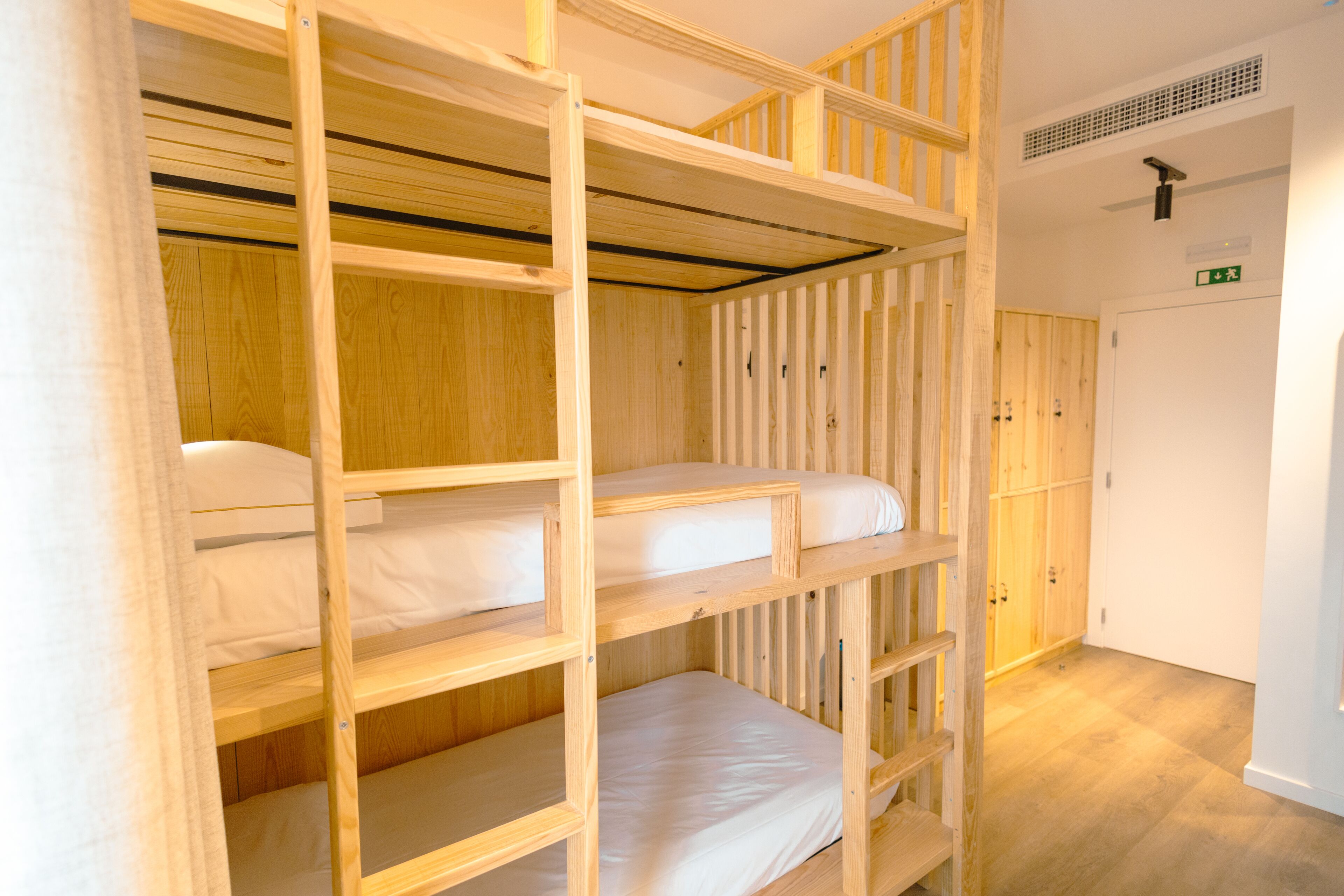 A bunk bed room with wooden railings and a white door with an emergency exit sign.