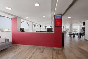 A modern reception area with a red wall, a computer desk, and a seating area. - Ramada By Wyndham Tampico Centro (Tampico)