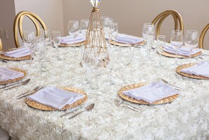 A round table set with white napkins, gold-rimmed plates, and clear glassware. - Ramada By Wyndham Tampico Centro (Tampico)