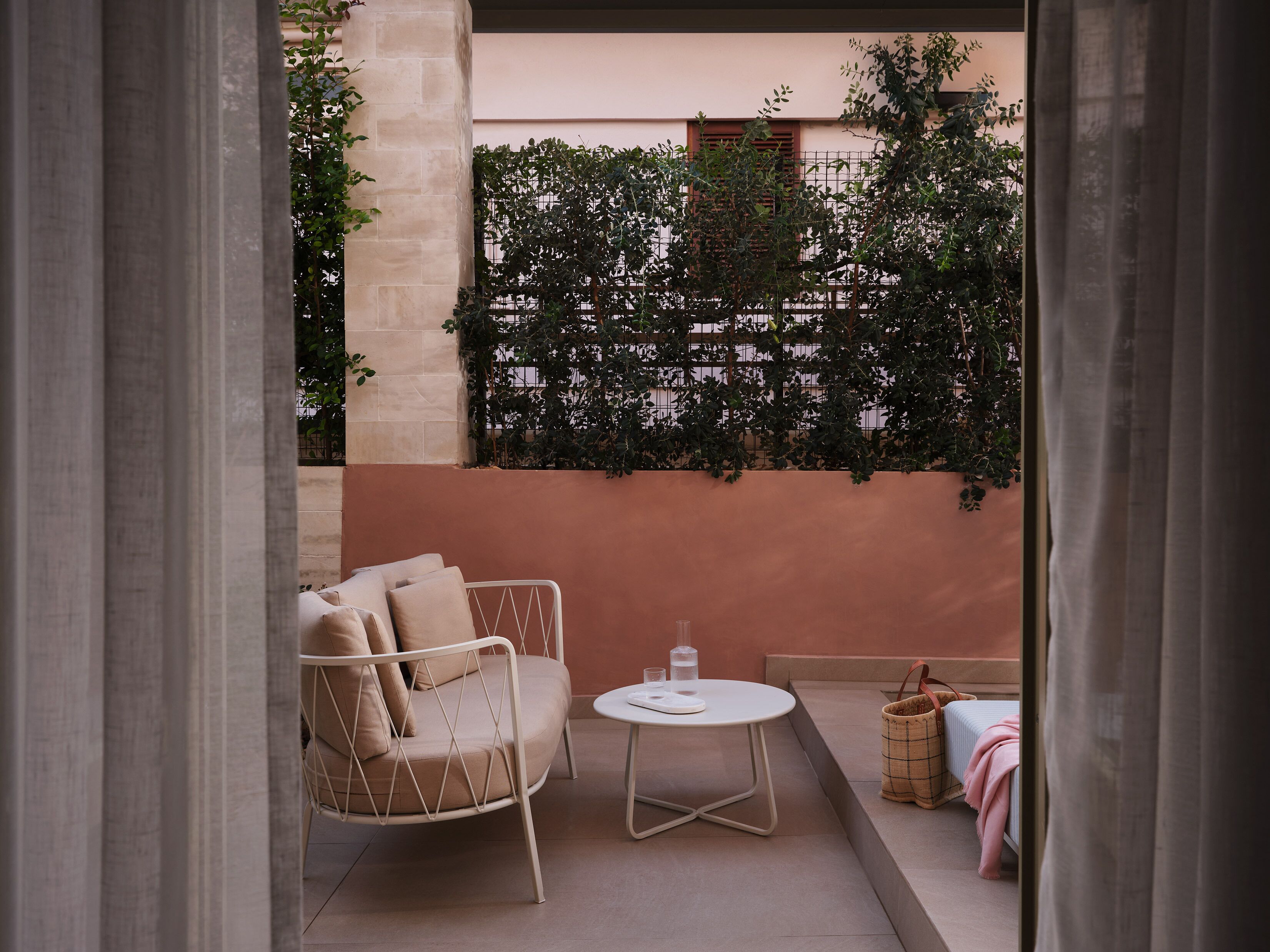 Un área de estar exterior moderna con una silla acolchada, una mesita redonda y una cesta.