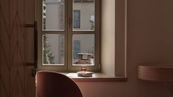 A room with a window, a chair, and a small table with books and a candle.