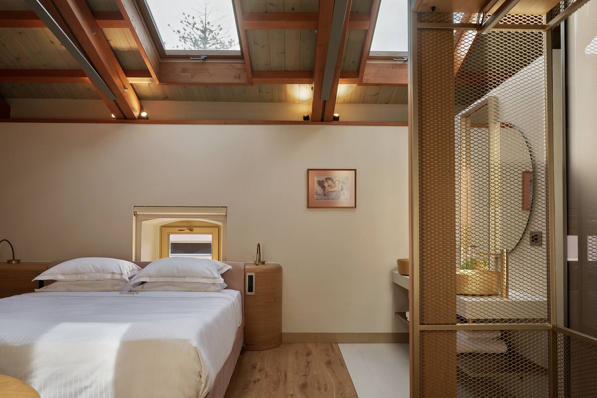 A bedroom with a bed, bedside table, and a window.
