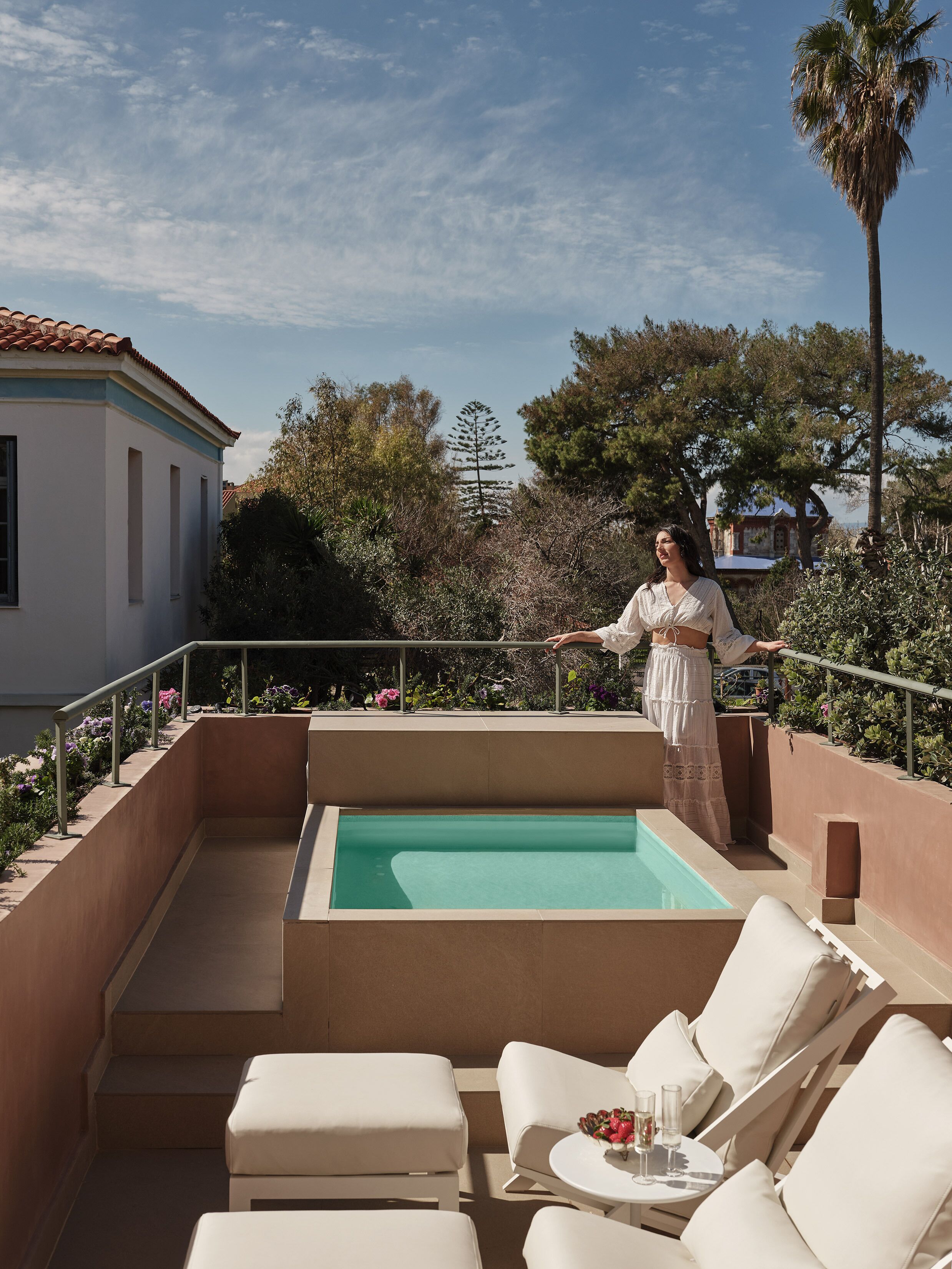 A pool area with lounge chairs and a person standing by the pool.