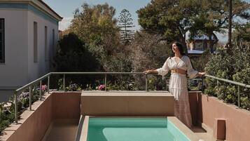 A pool area with lounge chairs and a person standing by the pool.