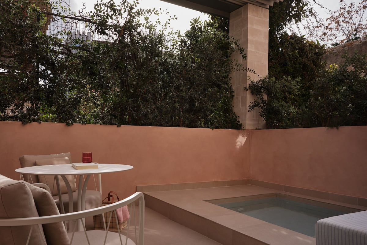 A private outdoor area with a pool, seating, and a view of dense foliage.