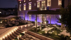 A modern building with a glass patio area, outdoor seating, and a staircase leading to an upper level. - Domus Blanc Boutique Hotel, Member of Domus Elegance Collection (Chania)