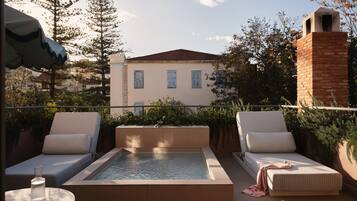 Eine Dachterrasse mit rechteckigem Pool, zwei Sitzbereichen mit Kissen und einem Backsteinsschornstein.