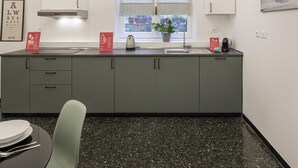 Eine moderne Küche mit grauen Schränken, einer Edelstahl-Spüle und einem Fenster mit Jalousien.