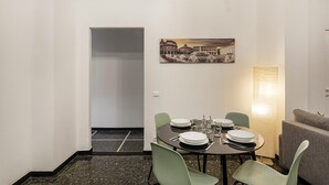 Ein Essbereich mit einem Tisch für vier Personen, grünen Stühlen und einem Stadtbild an der Wand.