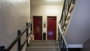 Eine Treppe mit Metallgeländer, die zu zwei roten Türen führt, über denen sich ein Schild befindet.