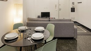 Ein modernes Hotelzimmer mit Essbereich, einer Couch, einem Fernseher und einer Tür.