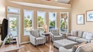 A spacious living room with large windows, a television, and a sailboat model. - 332 Ocean Point (Fripp Island)
