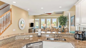 A kitchen with granite countertops, a dishwasher, and a dining area with a table and chairs. - 332 Ocean Point (Fripp Island)