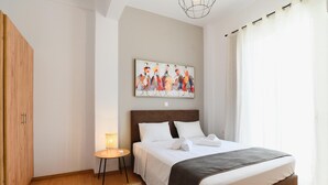 Una habitación de hotel con cama, una mesita con lámpara, un cuadro en la pared y un armario.