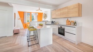 A modern kitchen with a central island, wooden cabinets, and a hanging pendant light. - Esperance - Brand New Luxury studio with parking! (Windermere)