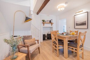 Un coin repas chaleureux avec une table en bois, des chaises et une suspension.
