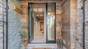 A wooden exterior with a glass door entrance, a doormat with a chicken design, and a small plant beside the door. - The Hut Retreat - Kirkby Lonsdale (Kirkby Lonsdale)