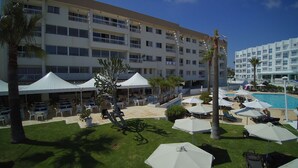 A hotel courtyard with outdoor seating, a pool, and multiple balconies. - Pola Costa Beach Hotel Apartment (Paralimni)