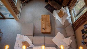 A cozy living room with a sofa, a coffee table, and a fireplace. There are three light bulbs on the floor. - Cozy Kettlebrook 2BR: Ski Access, Fireplace & Deck (Ludlow)