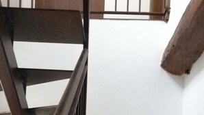A staircase with wooden railings and metal handrails, leading to a landing with a white wall and a wooden beam. - Cà DA MOÆ 1 - Very Central (Chiavari)