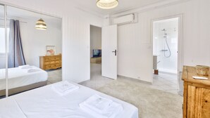 Een hotelkamer met twee bedden, een houten dressoir, een spiegel, een douche en een hanglamp.
